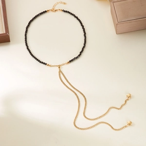 Dettaglio della collana di perline con nappe a stella dorata su fondo beige caldo