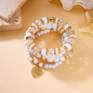 Details von mehrlagigen Boho-Armbändern mit weißen Kristallen und goldenem Herzanhänger