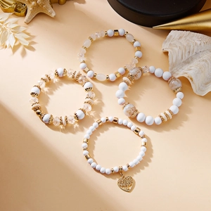 Detail von mehrlagigen Boho-Armbändern mit goldenem Lebensbaum-Herzanhänger