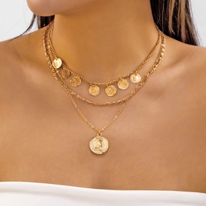 Détail d'un collier doré à trois rangs avec des pendentifs pièces et une chaîne torsadée