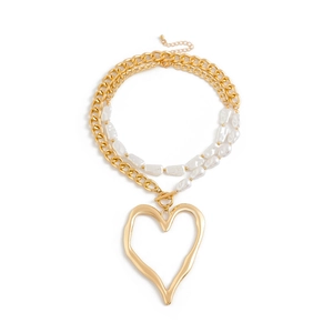 Close-up of golden chunky chain necklace with baroque pearls and large heart pendant