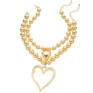 Detailed view of layered gold beaded necklace featuring abstract hollow heart pendants