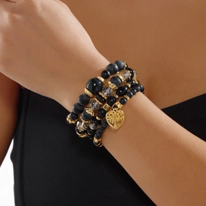 Nahaufnahme von mehrlagigem Boho-Perlenarmband-Set mit goldenem Herzbaum-Anhänger