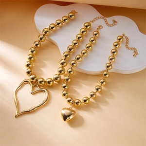 Detail of layered gold beaded necklaces featuring molten irregular heart-shaped pendants