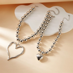 Detail of silver layered necklaces with hollow and solid heart pendants on beads chain