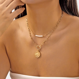 Détail d'un collier doré multicouche avec perles blanches et fermoir à bascule chic