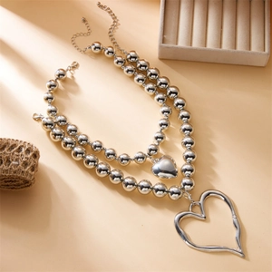 Detail showing double-layered silver bead necklace with solid and hollow heart pendants
