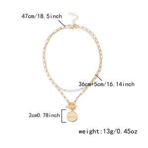 Détail d'un collier doré double rang avec pendentif pièce, perles et fermoir à bascule