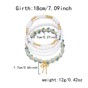 Detalle de set de cuatro pulseras con perlas sintéticas, cuentas jaspeadas y lazo dorado
