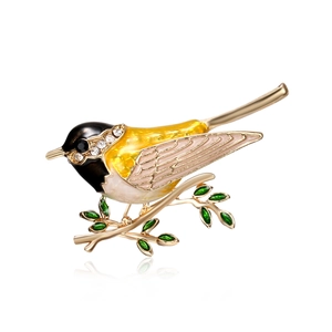 Exquisite bird brooch with yellow enamel on a golden branch with crystal details
