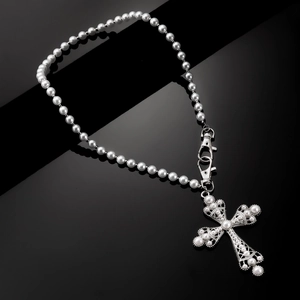 Detail of silver cross pendant with embedded pearls and lobster clasps on black background