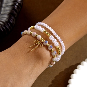 Detalle de pulseras de perlas en capas con cerámica azul y un lazo dorado elegante