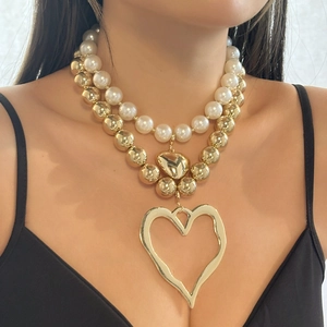 Layered gold bead and pearl necklace featuring an irregular heart pendant on a model