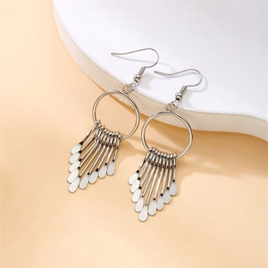 Detail view of silver metal hoop earrings with elegant hanging fringe paddle tassels