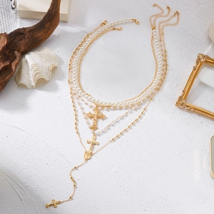 Détails d'un collier triple rang avec perles et pendentifs croix avec pampilles