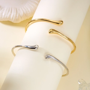 Vue détaillée de bracelets minimalistes ondulés or et argent sur un support blanc