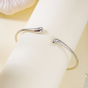 Détail macro du bracelet jonc argenté en C avec embouts en goutte sur support de vente