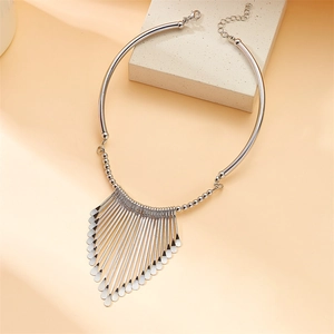 Detail view of bold silver tassel necklace with metallic fringe on stone pedestal