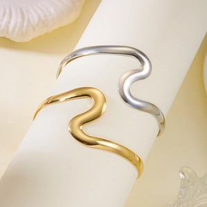 Détail de bracelets ondulés en métal doré et argenté sur un présentoir minimaliste