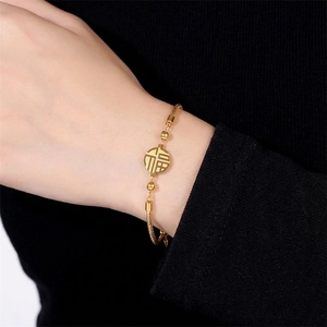 Elegant gold Fu character pendant bracelet with woven chain for women in a luxury style