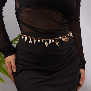 Detail of golden waist chain with sea shells, starfish charms and pearls on a model