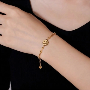 Detail of gold Fu character bracelet with bead chain and heart charm on wrist