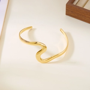 Gros plan du bracelet jonc doré aux formes ondulées avec une finition polie brillante
