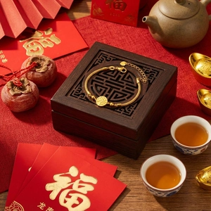 Detail of gold Fu bracelet with woven chain against festive Chinese New Year backdrop