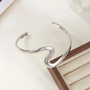 Gros plan d'un bracelet jonc ouvert argenté minimaliste avec finition miroir polie