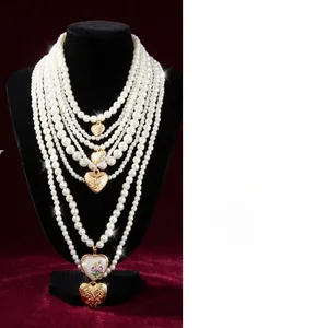 Détail du collier de perles baroques avec breloques cœur et pendentif rose