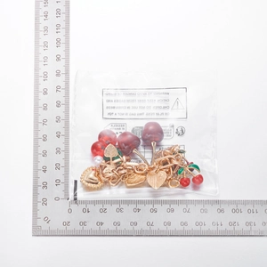 Detail view of cherry and heart pendant necklace with size measurement on a scale