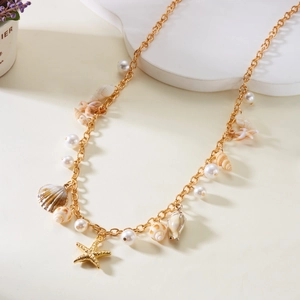 Detail of gold necklace featuring sea star, shells, and white pearls on neutral backdrop
