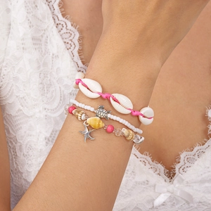Detail of bohemian ocean bracelet set featuring pink beads, sea shells and turtle charms
