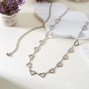 Detailed view of silver heart-shaped chain links with inlaid crystals and lobster clasp