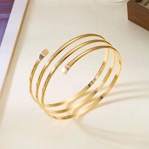 Gros plan d'un bracelet de bras spirale doré aux lignes métalliques polies irrégulières