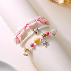 Close-up of Bohemian 3-piece bracelet set with starfish, turtle, and shell charms on a stand