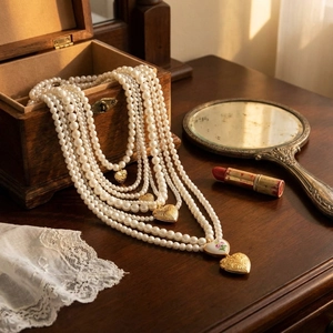 Colliers de perles baroques multicouches avec pendentif cœur doré sur une table en bois