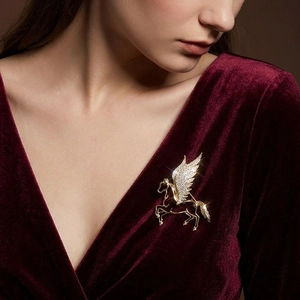 Detail of a vintage golden Pegasus brooch with sparkling crystals on burgundy velvet dress