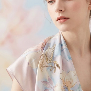 Detailed view of luxury gold Pegasus brooch with sparkling zircons on elegant silk clothing
