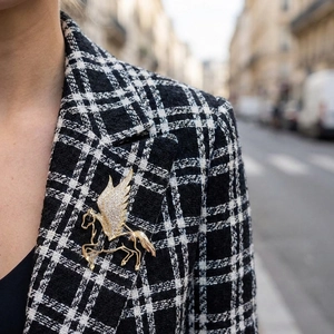 Detailed view of luxury Pegasus brooch with sparkling diamonds on a plaid suit blazer
