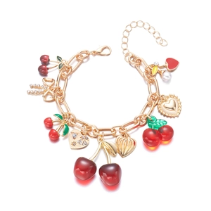 Detail of a gold-plated link necklace featuring red cherry, heart charms, and pearl accents