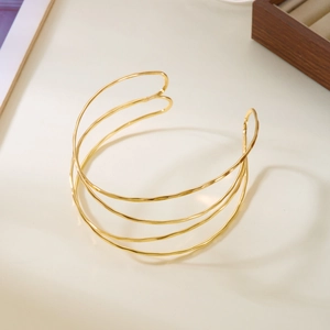 Gros plan d'un bracelet manchette doré multicouche avec texture de vagues irrégulières