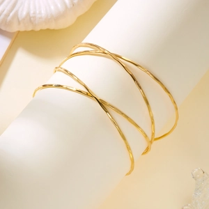 Détail du bracelet doré multicouche à texture martelée irrégulière sur support blanc