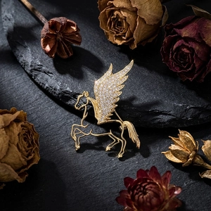 Detailed macro view of a gold Pegasus brooch with crystal wings on black stone decor