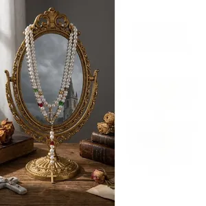 Gros plan d'un collier de perles gothique avec pendentif croix dorée sur un miroir ancien