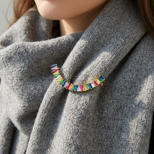 Détail d'une broche en cristal arc-en-ciel épinglée sur une écharpe en maille grise