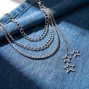 Punk multilayer silver waist chain with star pendants on denim fabric background