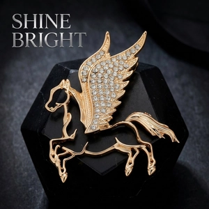 Luxury gold Pegasus brooch with sparkling white rhinestones on a black background