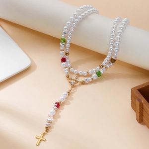 Détail du chapelet en perles blanches avec cristaux colorés et pendentif croix dorée