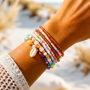Close-up of bohemian layered beaded bracelets with rainbow seeds, pearls and shell pendant